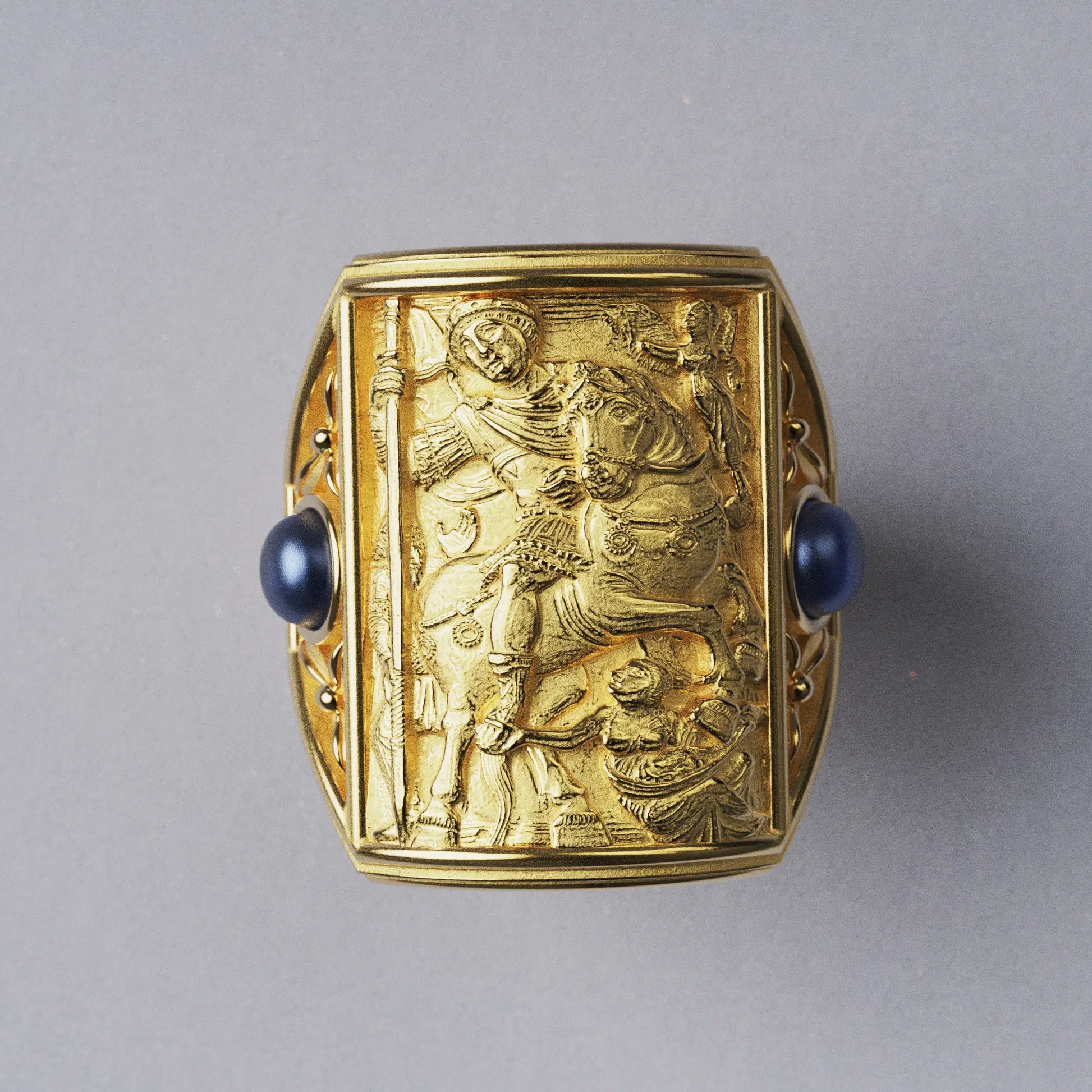 Gold ring with cabochon sapphires and Byzantine-style relief sculpture, featuring intricate details and a regal design.