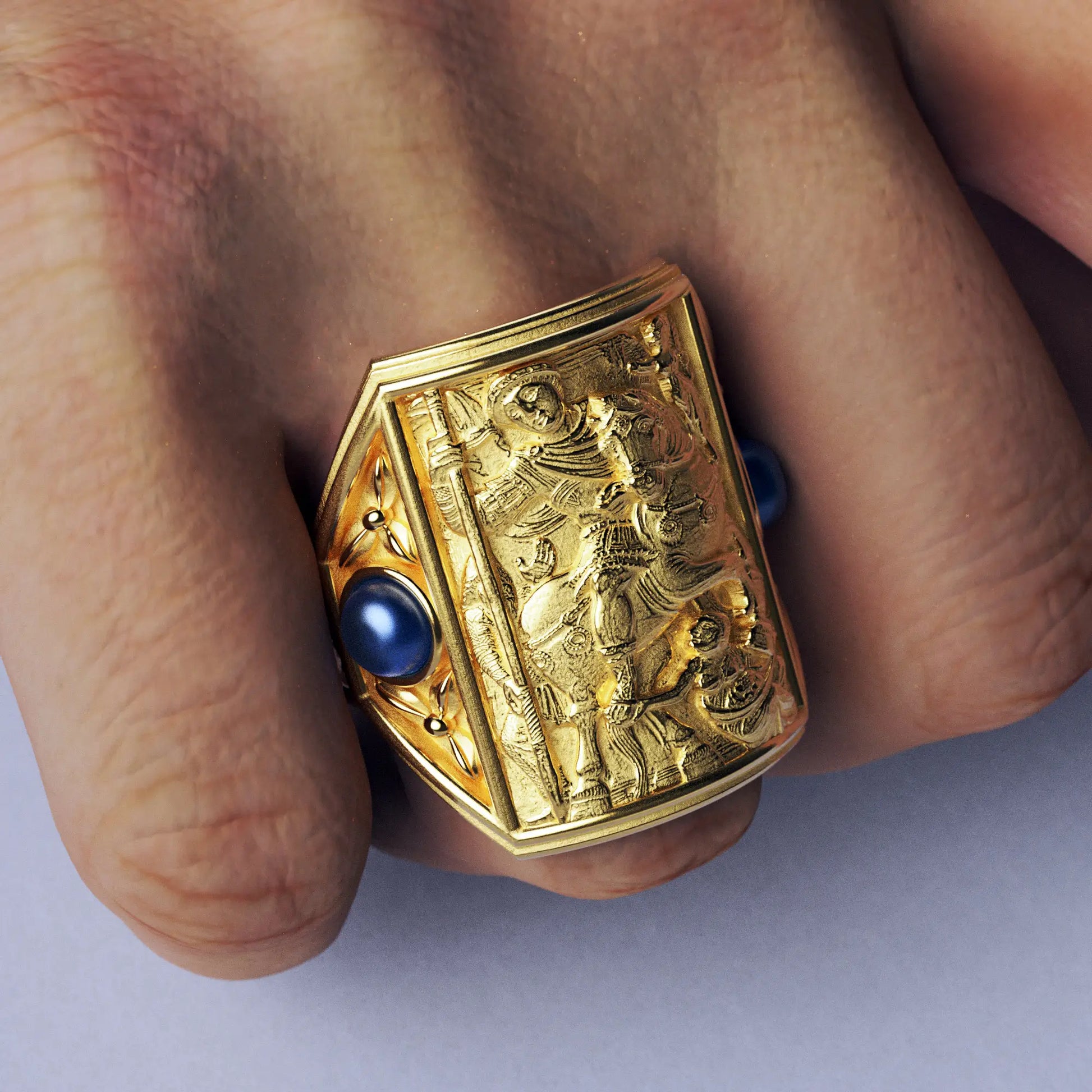 Gold ring with cabochon sapphires and Byzantine-style relief sculpture, featuring intricate details and a regal design.