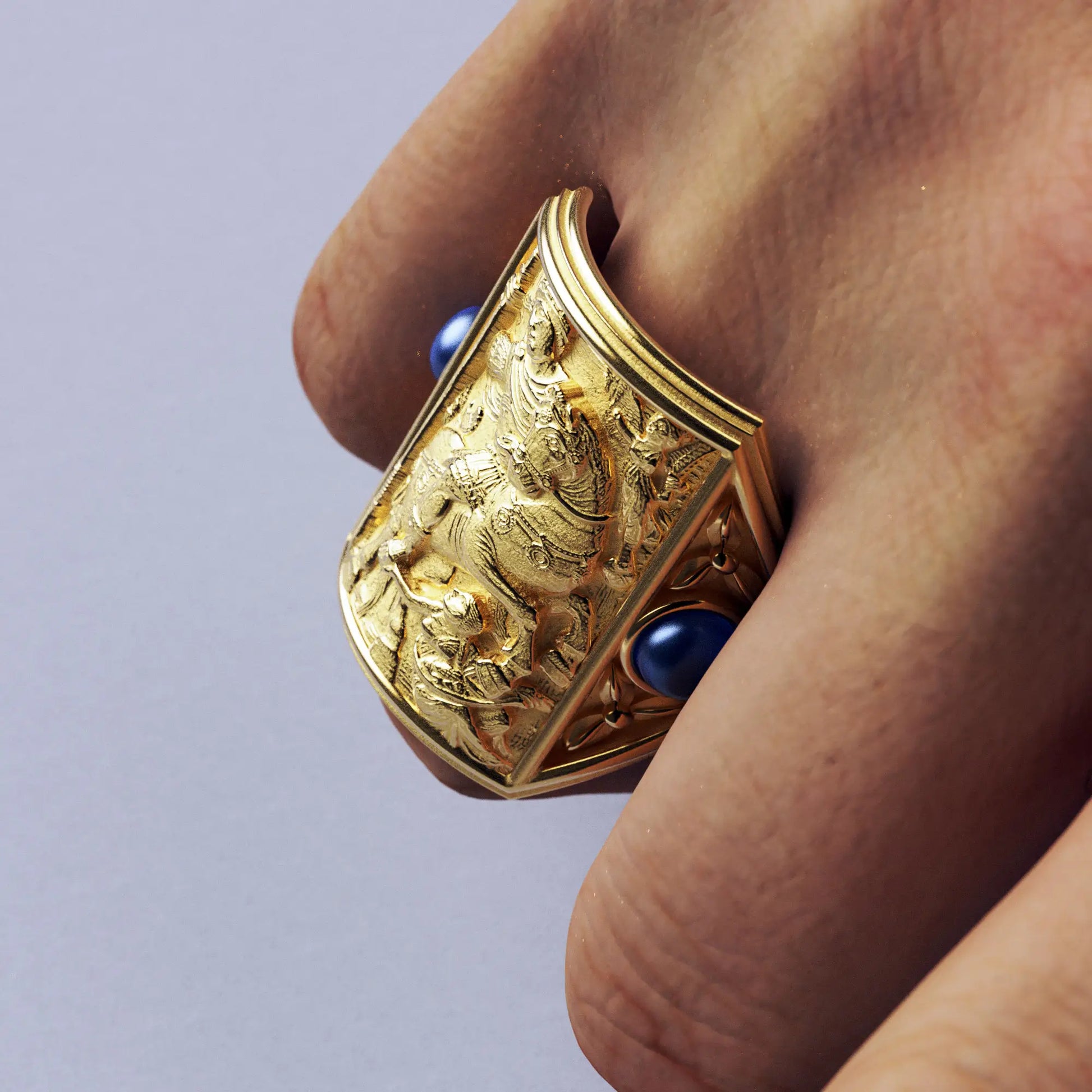 Gold ring with cabochon sapphires and Byzantine-style relief sculpture, featuring intricate details and a regal design.