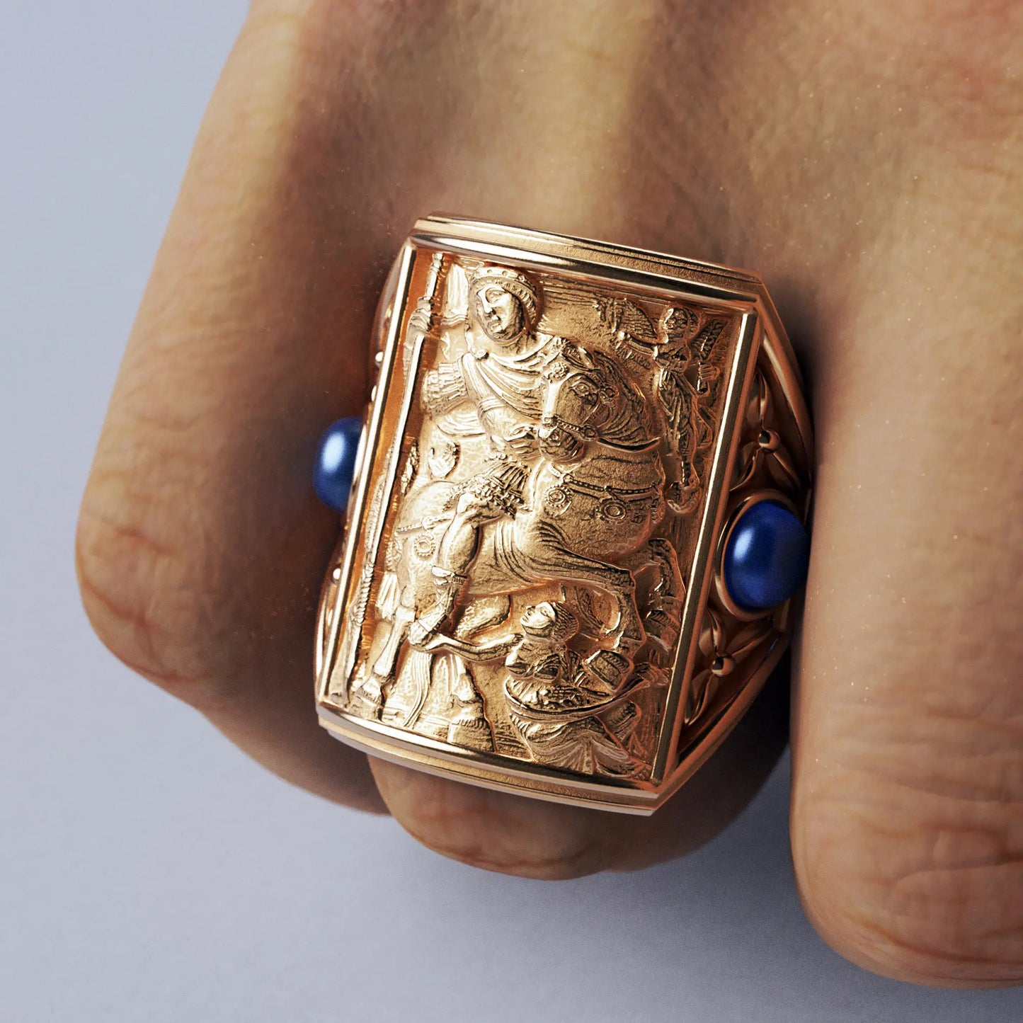 Gold ring with cabochon sapphires and Byzantine-style relief sculpture, featuring intricate details and a regal design.