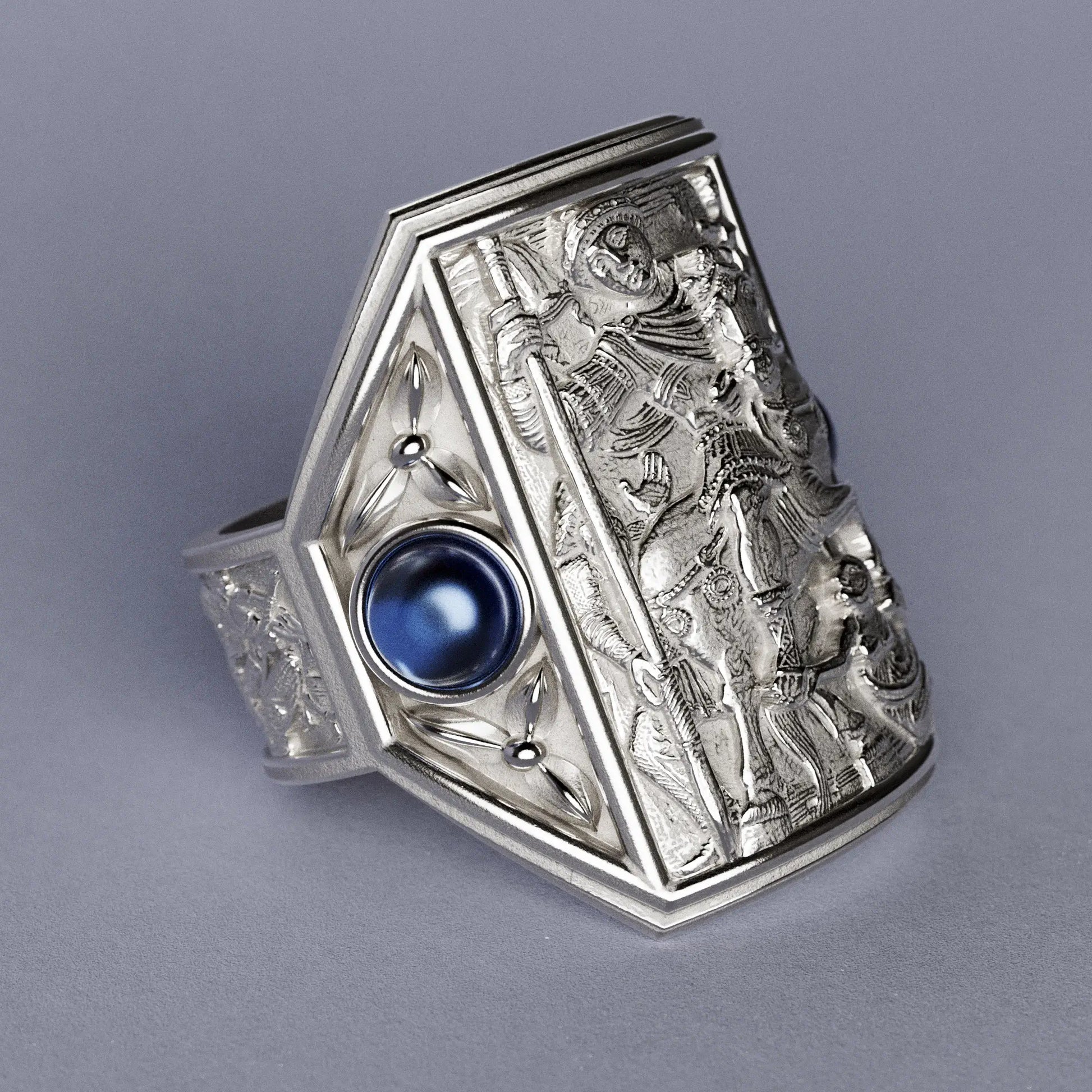 Gold ring with cabochon sapphires and Byzantine-style relief sculpture, featuring intricate details and a regal design.