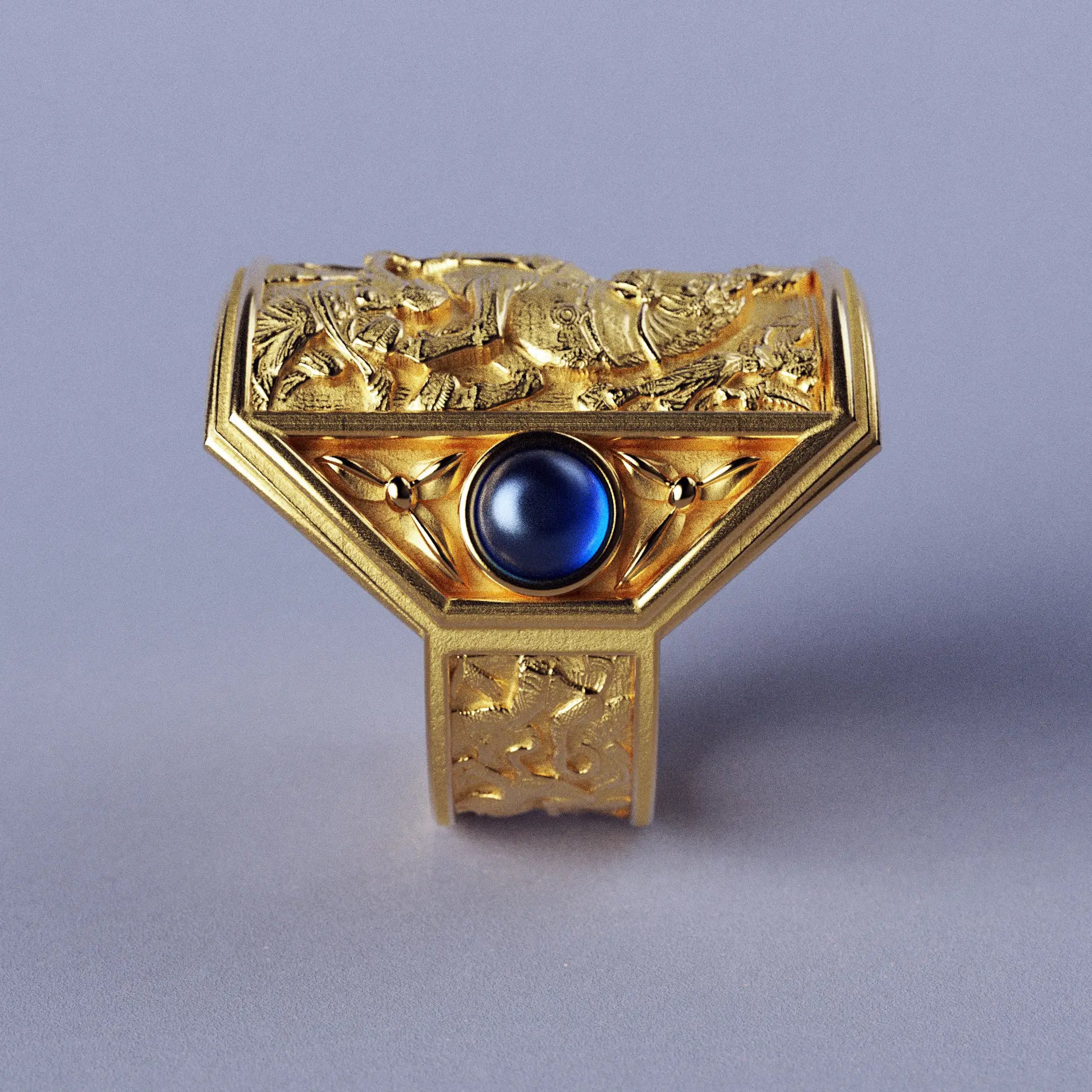 Gold ring with cabochon sapphires and Byzantine-style relief sculpture, featuring intricate details and a regal design.