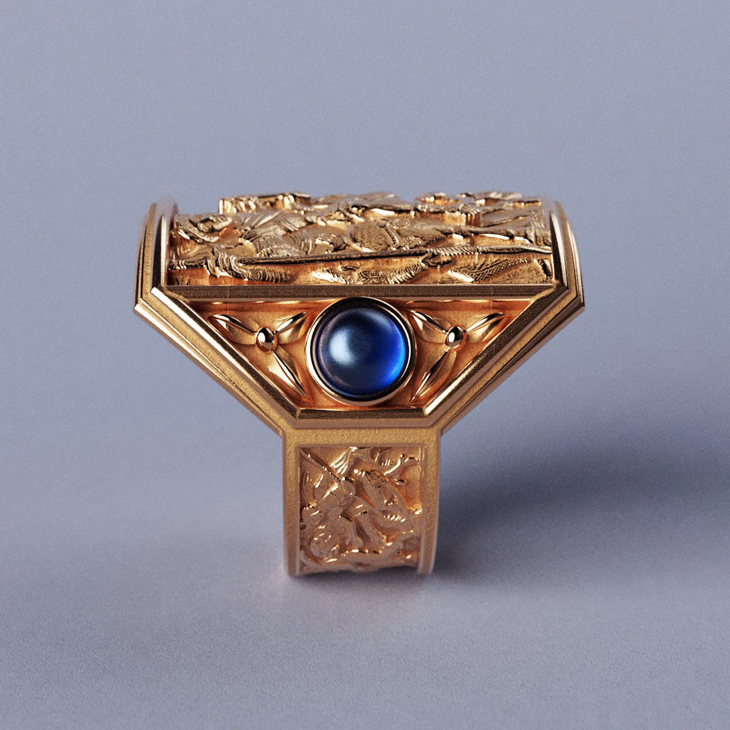 Gold ring with cabochon sapphires and Byzantine-style relief sculpture, featuring intricate details and a regal design.