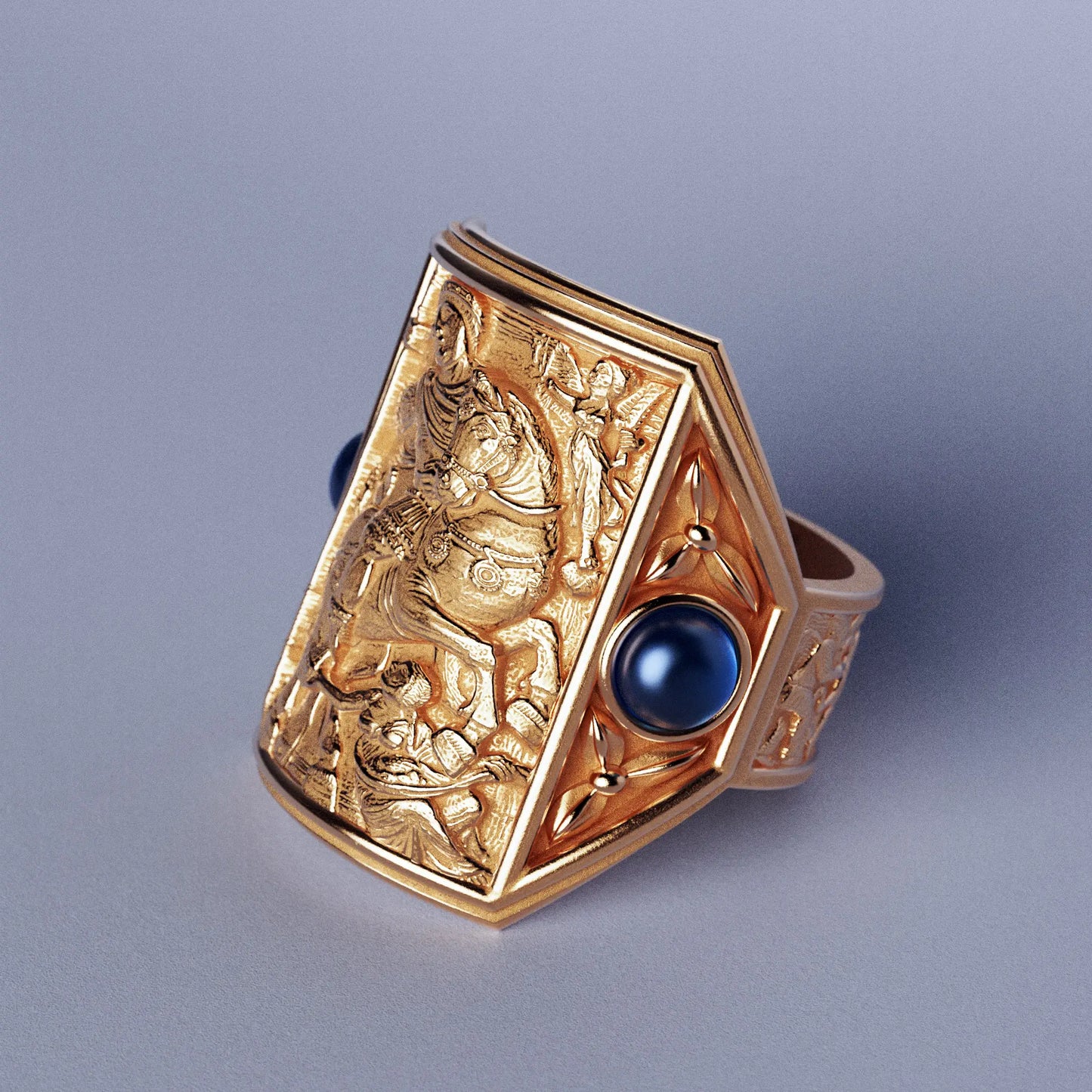 Gold ring with cabochon sapphires and Byzantine-style relief sculpture, featuring intricate details and a regal design.