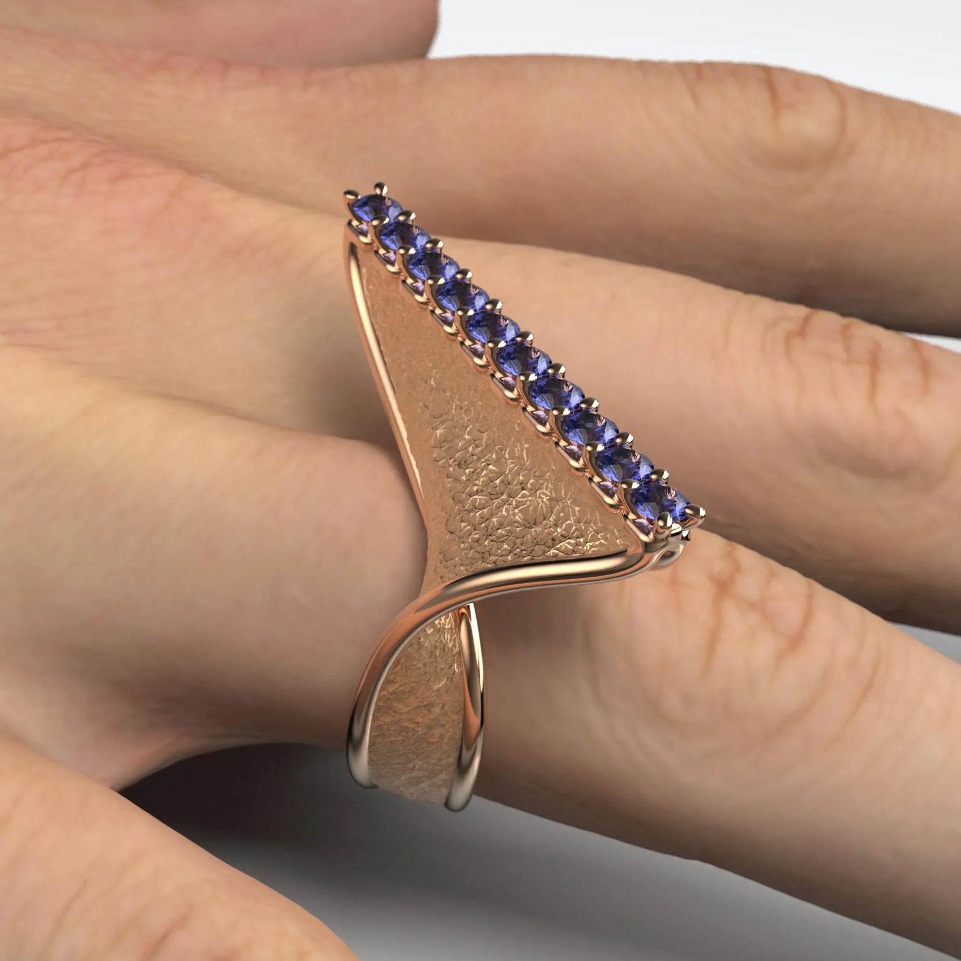 A twisted gold ring with an earth-textured surface and polished edges, featuring 10 round natural tanzanites set along the top ridge, available in 14k or 18k gold.