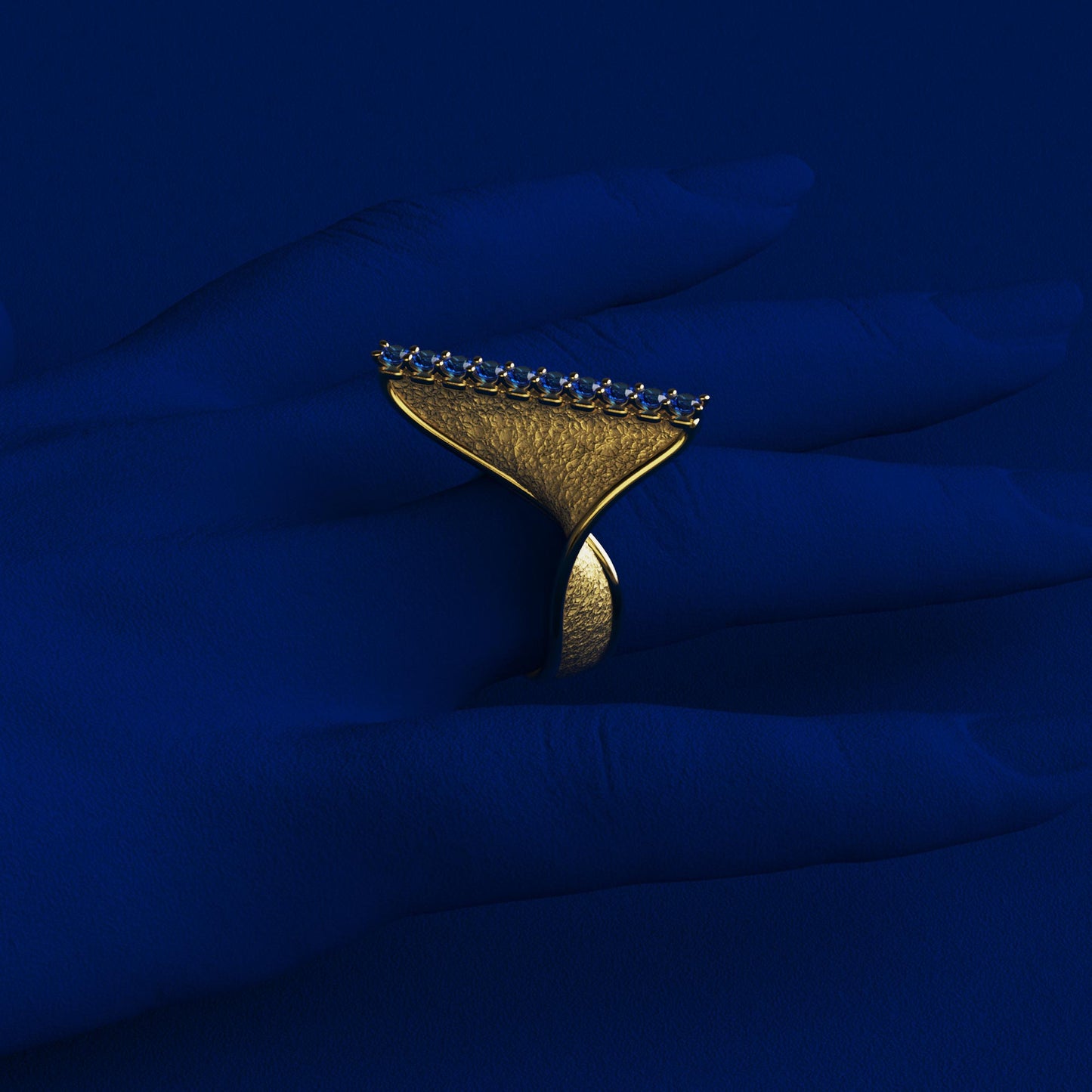 A handcrafted 18k gold ring featuring a modern twisted design with 10 round blue sapphires set along the top ridge. Polished edges with an earth-textured surface.