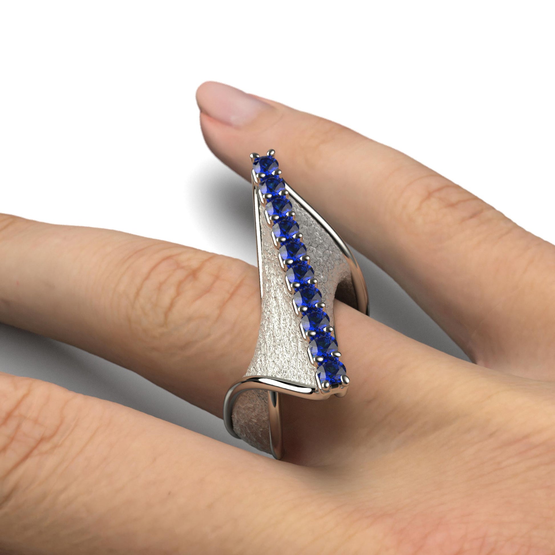 A handcrafted 18k gold ring featuring a modern twisted design with 10 round blue sapphires set along the top ridge. Polished edges with an earth-textured surface.