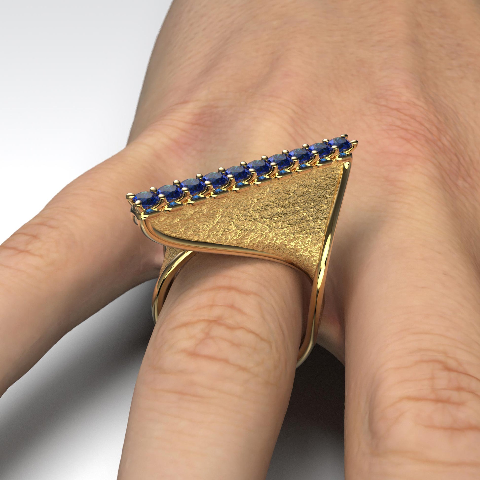 A handcrafted 18k gold ring featuring a modern twisted design with 10 round blue sapphires set along the top ridge. Polished edges with an earth-textured surface.