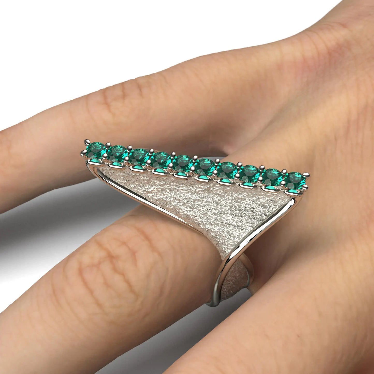 A modern twisted gold ring featuring 10 round natural emeralds set along the top ridge, with polished edges and an earth-textured surface.