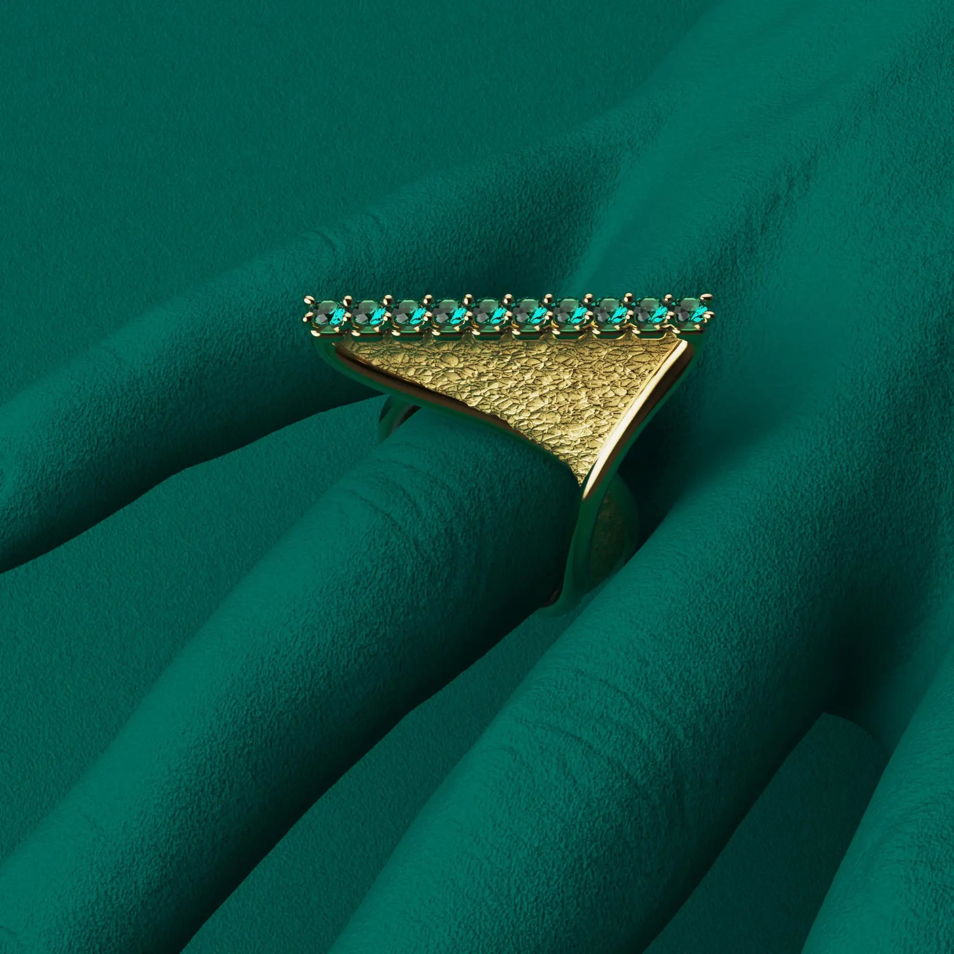 A modern twisted gold ring featuring 10 round natural emeralds set along the top ridge, with polished edges and an earth-textured surface.