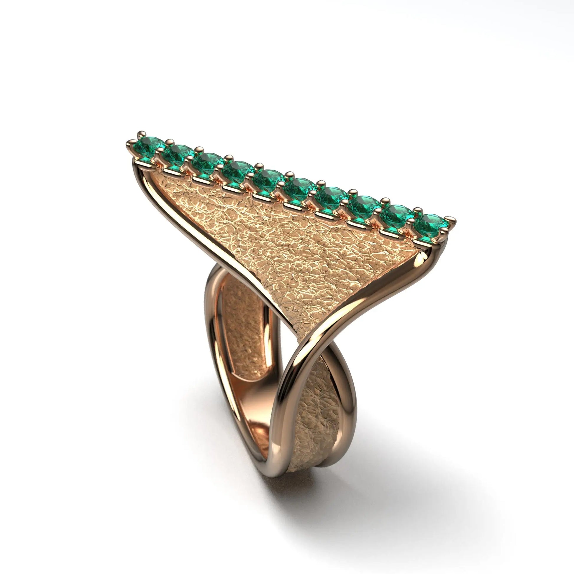 A modern twisted gold ring featuring 10 round natural emeralds set along the top ridge, with polished edges and an earth-textured surface.