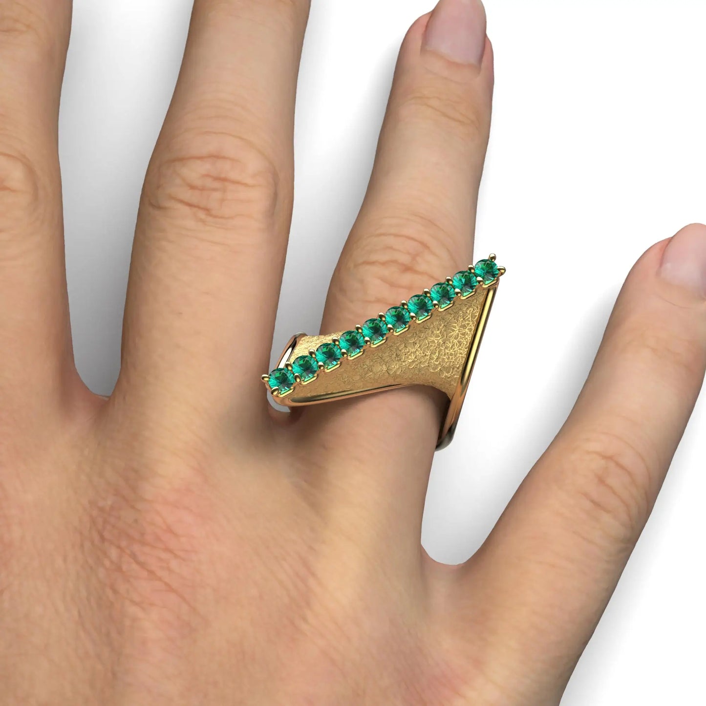 A modern twisted gold ring featuring 10 round natural emeralds set along the top ridge, with polished edges and an earth-textured surface.