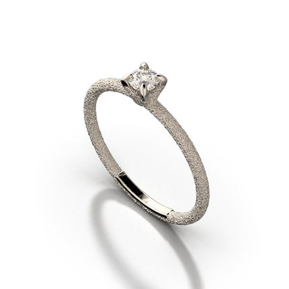 A stunning Italian handmade ring featuring a round, natural white diamond, measuring approximately 3.5mm in diameter and weighing 0.16 carats. The diamond is set on a sleek, handcrafted 18k or 14k solid gold band, meticulously textured to create a striking sparkle effect. The band is approximately 1.6mm wide and 1.6mm thick, enhancing the diamond's brilliance.